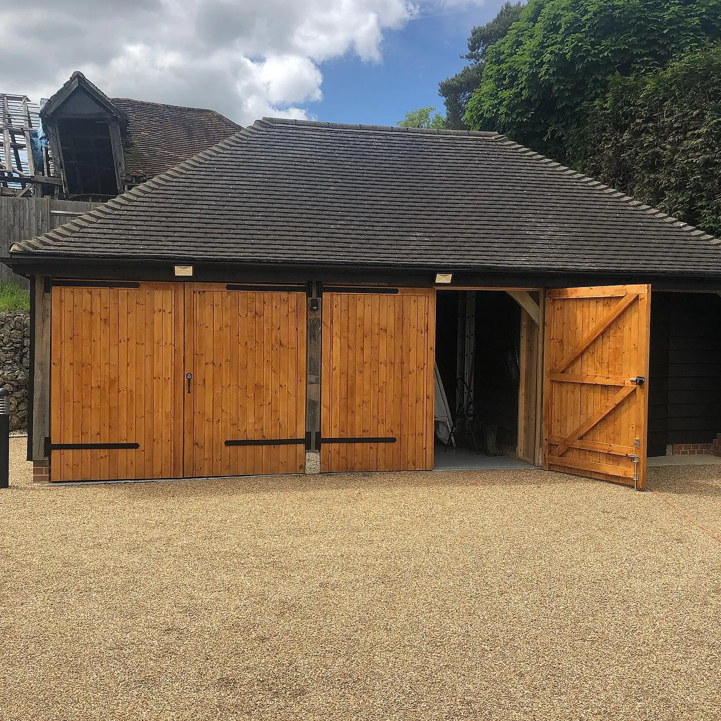a large wooden garage with a black roof
